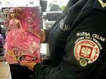 Funkcjonariusz Służby Celno-Skarbowej trzymający w rękach niebezpieczną zabawkę w postaci lalki zapakowaną w przezroczyste opakowanie