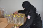Funkcjonariusz liczy butelki z podejrzanym alkoholem.