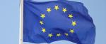 Flaga Unii Europejskiej. Na fladze przedstawiony jest okrąg złożony z dwunastu złotych gwiazd na błękitnym tle.