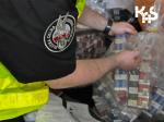 Funkcjonariusz śląskiej KAS w odblaskowej kamizelce układa worki zawierające nielegalne papierosy