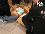 fotografia przedstawia funkcjonariuszy Służby Celno-Skarbowej klęczącego nad otwartym opakowaniem kartonowym zawierającym leki.