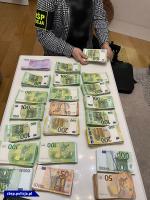 na stole leżą różnego rodzaju waluty, przy stole siedzi osoba