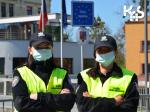 stojący obok siebie dwóch funkcjonariuszy, ubranych w mundury Śłużby Celno-Skarbowej i dodatkowo w odblaskowe kamizelki, na twarzach maseczki.
