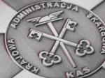 Znak graficzny Krajowej Administracji Skarbowej: dwa skrzyżowane klucze na tle laski z uskrzydlonym kapeluszem Merkurego, na emblemacie w kształcie koła, z napisem na okręgu 
