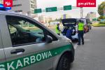 Na pierwszym planie samochód Śląskiego Urzędu Celno-Skarbowego, w tle dwóch funkcjonariuszy i taksówkarz stoją przy samochodzie.