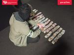 Funkcjonariusz Służby Celno-Skarbowej układa banknoty na podłodze.