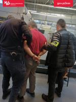 dwóch funkcjonariuszy Służby Celno-Skarbowej prowadzący zatrzymanego mężczyznę, który ma założone kajdanki