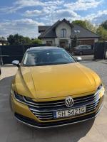 Ciemnożółty arteon stoi na podjeździe posesji, widok od przodu, słoneczny dzień