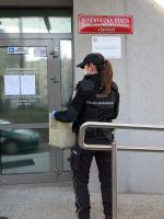 Fotografia przedstawia funkcjonariuszkę Służby Celno-Skarbowej wnoszącej do budynku Wojewódzkiej Stacji Sanitarno-Epidemologicznej w Katowicach skrzynkę z alkoholem